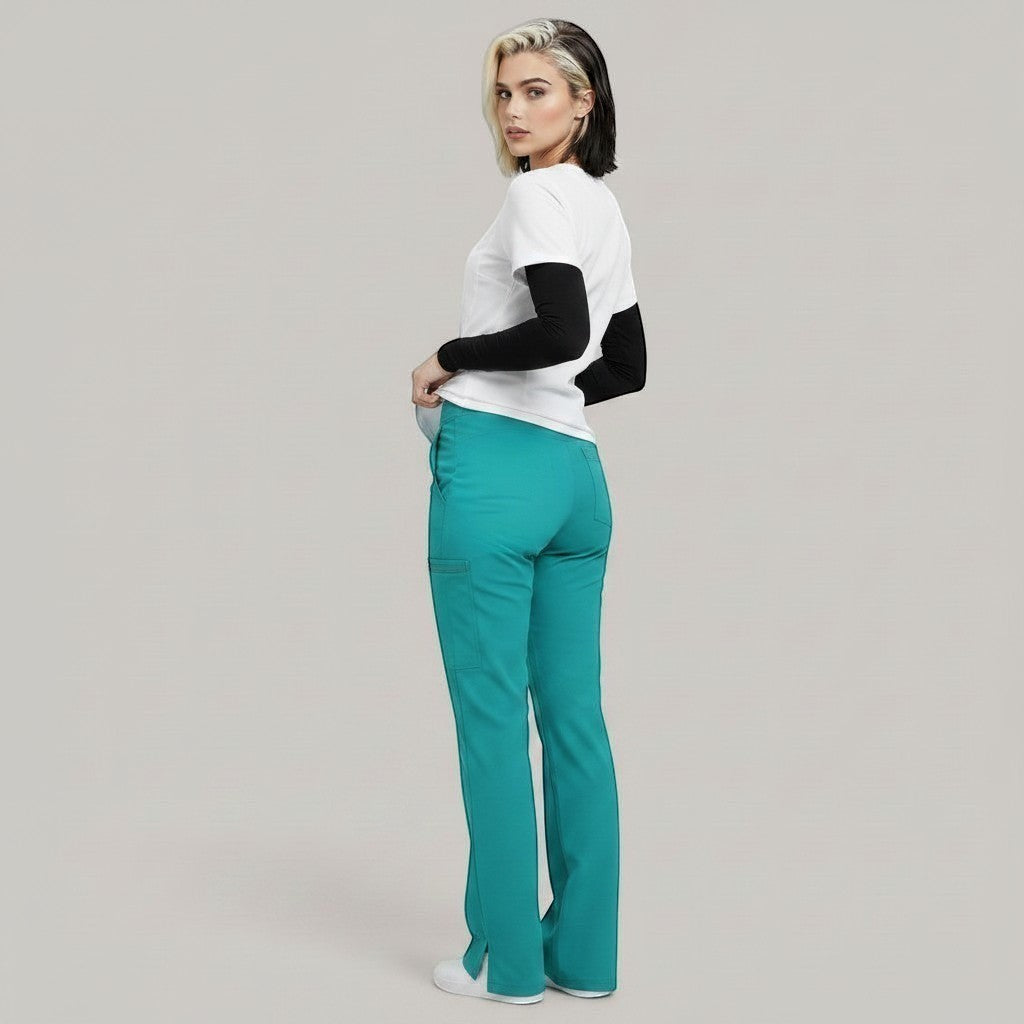 Model wearing Élaura Faye cargo pants in teal with side pockets and hem slits, paired with a white and black top.