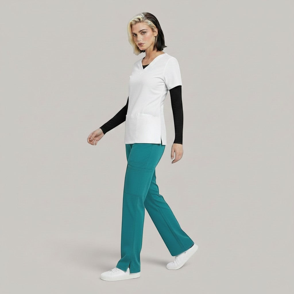 Model wearing Élaura Faye cargo pants in teal with a white scrub top and black long-sleeve base layer.