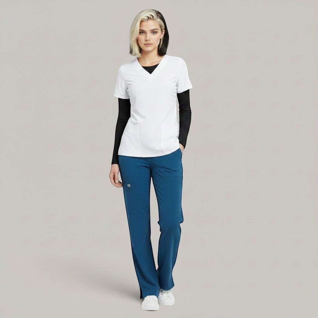 Model wearing Élaura Faye cargo pants in teal blue with a white v-neck scrub top and black long-sleeve base layer.